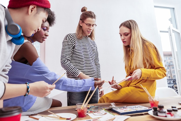 Vreugdevol voelen. Vier creatieve getalenteerde studenten van de kunstacademie die zich vrolijk voelen tijdens hun studie