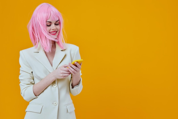 Vreugdevolle glamoureuze vrouw met roze pruik die aan de telefoon praat gele achtergrond foto van hoge kwaliteit