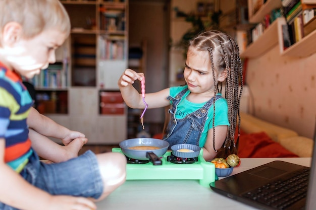 Foto vreugdevolle kinderen met eten op tafel.