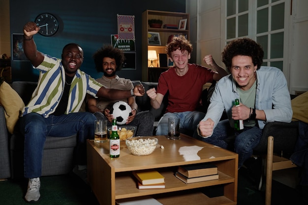 Vreugdevolle mannen kijken naar een sportevenement op tv.