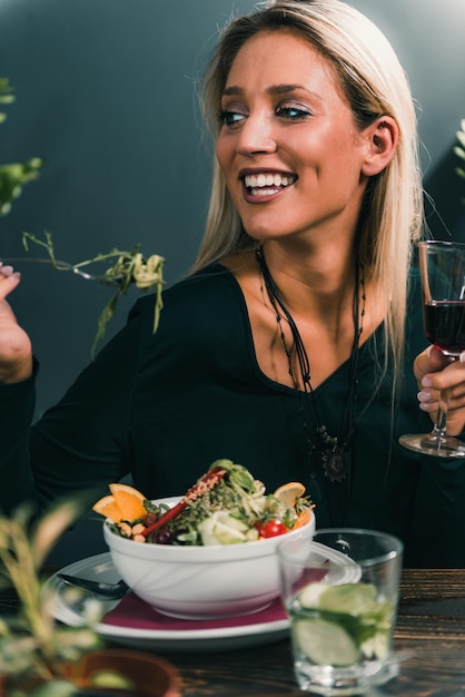Vreugdevolle vrouw die eten eet aan tafel in een restaurant
