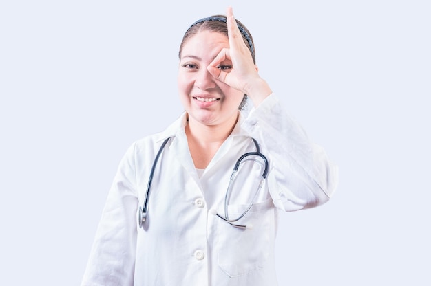 Vreugdevolle vrouwelijke arts gebaar goedkeuring geïsoleerd Jonge vrouwelijke arts goedkeuring met de vinger op geïsoleerde achtergrond