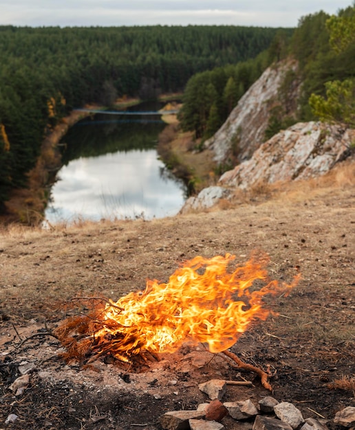 Vreugdevuur branden tegen de achtergrond van de rivierkliffen en naaldbos in de herfst Landschap