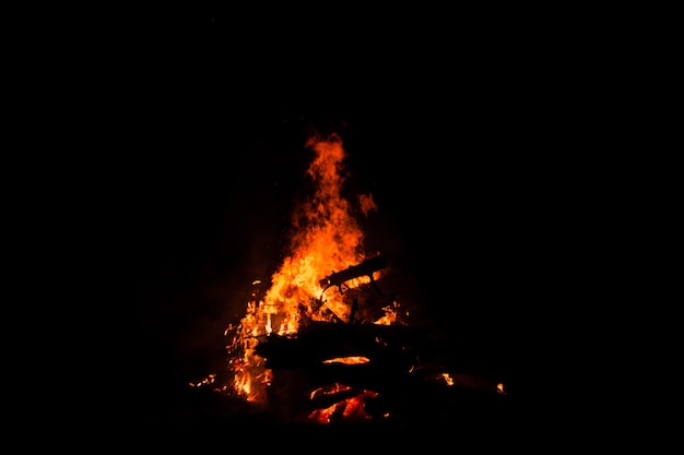 Vreugdevuur brandende bomen 's nachts. Vreugdevuur dat helder brandt, warmte, licht, kamperen, groot vreugdevuur.