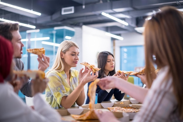 Vriendelijk divers multi-etnisch zakenteam dat samen pizza eet in een opstartkantoor, multiraciale collega's personeelsgroep genieten van pauze praten lachen tijdens de lunch tijdens de vergadering