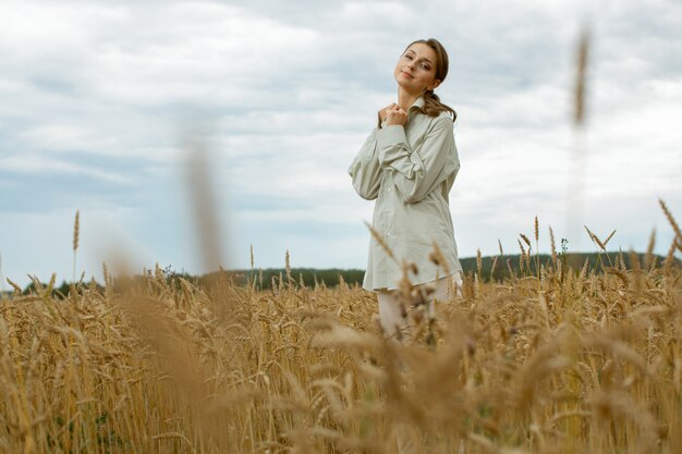 Vriendelijk en lief meisje in lichte kleren staan in het midden van het veld.