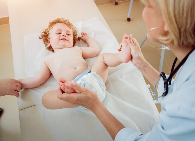 Vriendelijke arts kinderarts met geduldig kind in de kliniek