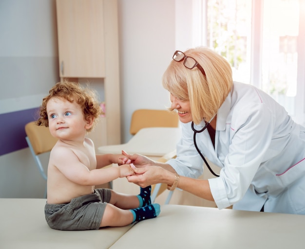 Vriendelijke arts kinderarts met geduldig kind in de kliniek