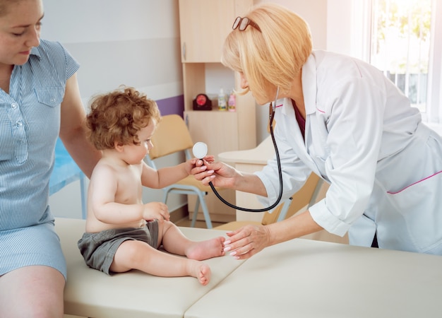 Vriendelijke arts kinderarts met geduldig kind in de kliniek