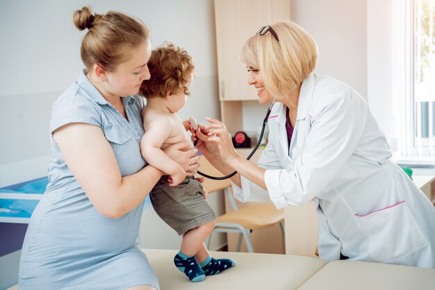 Vriendelijke arts kinderarts met geduldig kind in de kliniek