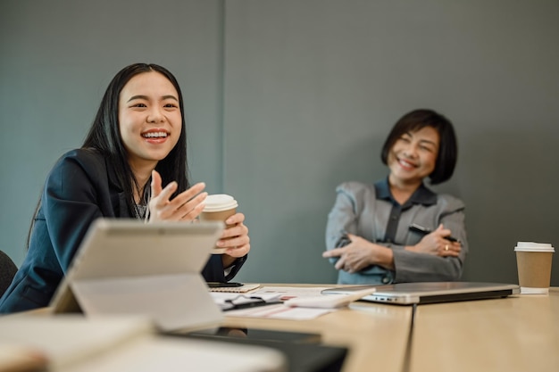 Vriendelijke Aziatische vrouwelijke manager die met collega's praat tijdens een pauze in de vergaderzaal