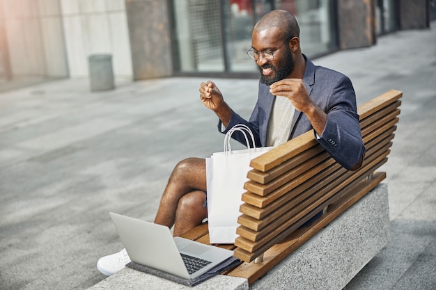 Vriendelijke bebaarde man die glimlach op zijn gezicht houdt terwijl hij naar het scherm van zijn laptop kijkt