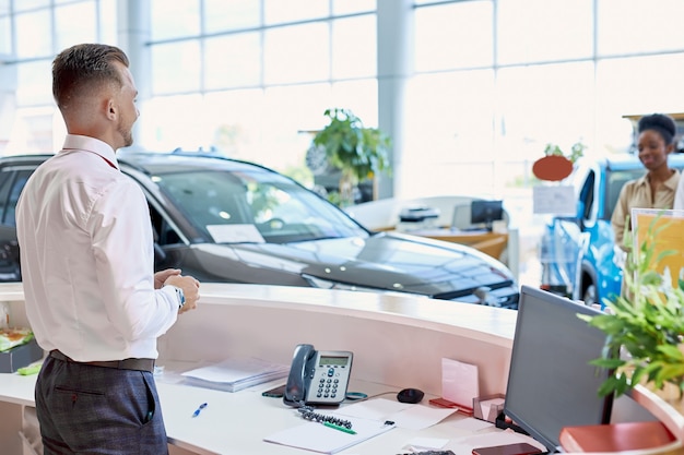 vriendelijke blanke manager groet klanten in autosalon