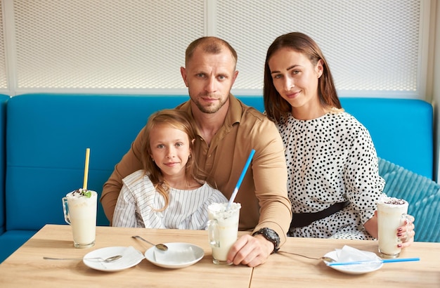 Vriendelijke familie met milkshakes in het café?