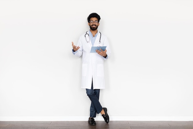 Vriendelijke jonge arts uit het Midden-Oosten die op een witte achtergrond poseert