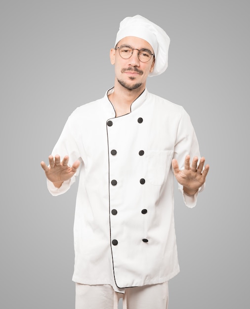Vriendelijke jonge chef-kok doet een gebaar van kalmte bewaren