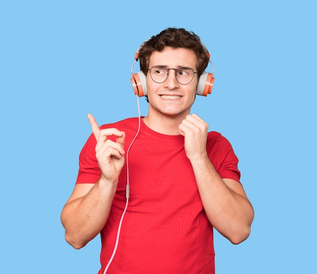 Vriendelijke jonge man die een verwonderd gebaar maakt en met zijn vinger omhoog wijst