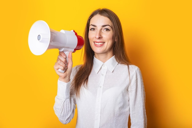 Vriendelijke jonge vrouw houdt een megafoon in haar handen op een gele achtergrond Hulp bij het inhuren van concept gezocht Banner