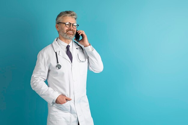 Foto vriendelijke knappe dokter heeft een telefoontje met kopieerruimte voor de patiënt