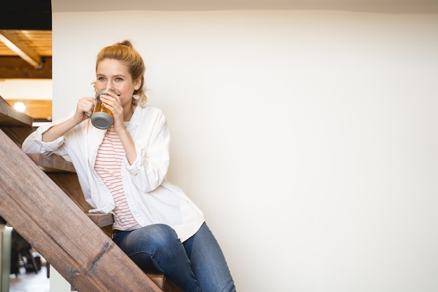 Vriendelijke vrouw zittend op houten trappen en genietend van haar weekend