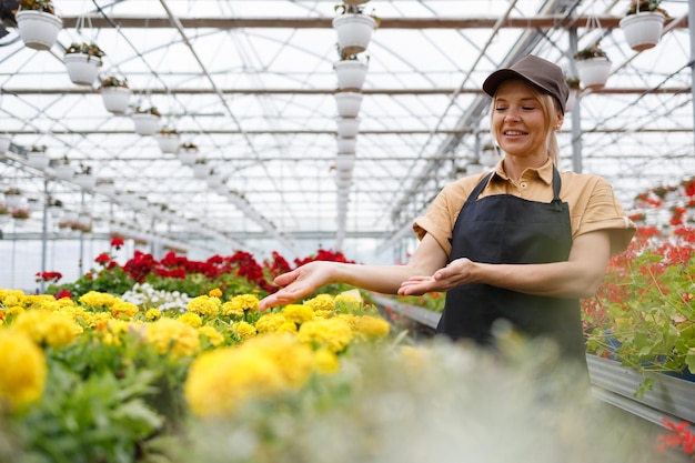 Vriendelijke vrouwelijke bloemist in een kas