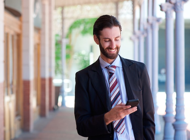 Vriendelijke zakenman lachend met mobiele telefoon