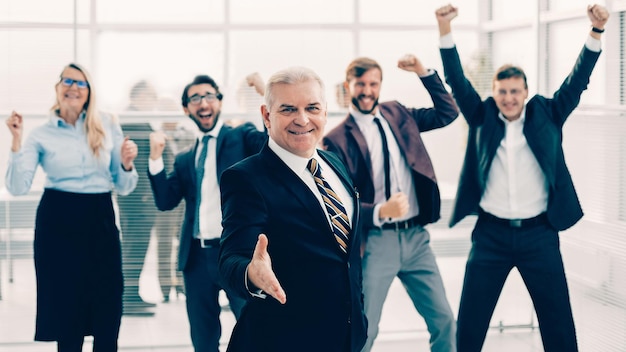 Vriendelijke zakenman op de achtergrond van een gelukkig zakelijk team