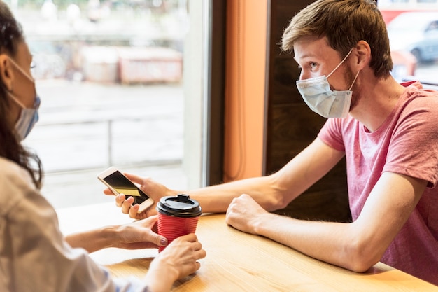 Vrienden chatten terwijl ze medische maskers dragen in een pub