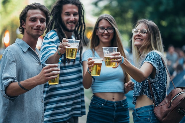 Vrienden die bier drinken en plezier hebben op muziekfestival
