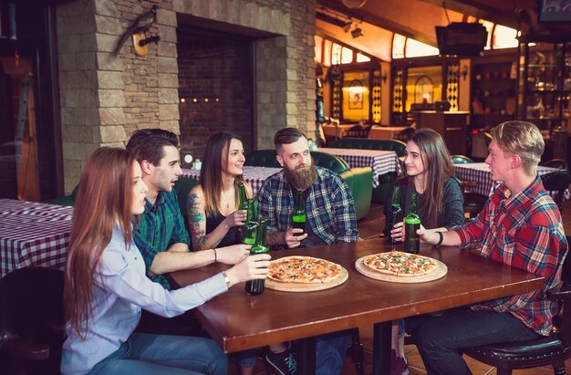 Vrienden die dranken hebben en pizza's in een bar eten