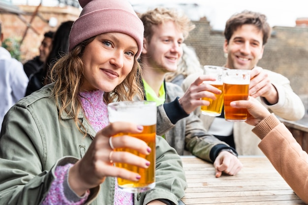 Vrienden die en met bier bij bar drinken roosteren