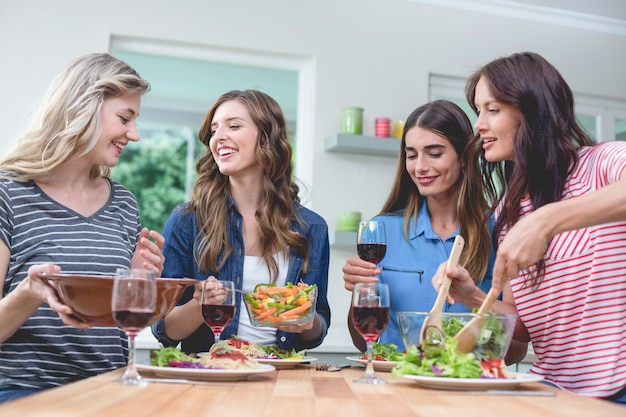 Vrienden die glas rode wijn houden terwijl het hebben van maaltijd