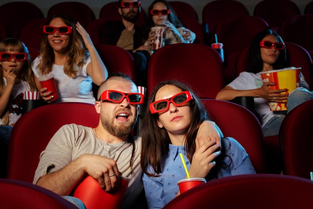 Vrienden die in de bioscoop zitten, kijken naar een film die popcorn eet en water drinkt.