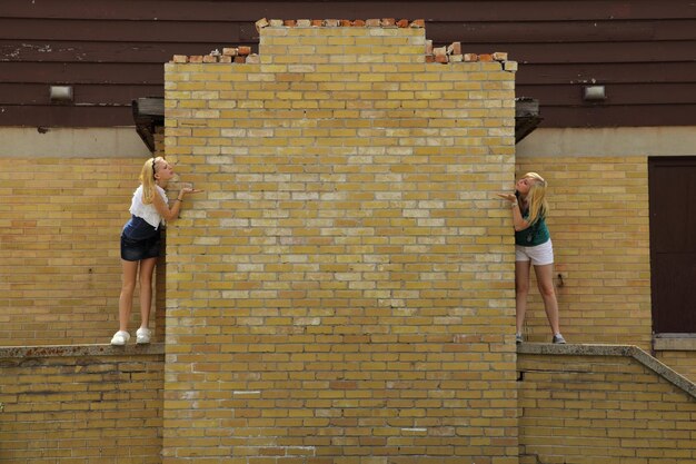 Foto vrienden die kussen terwijl ze op de muur staan.