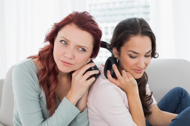 Vrienden die muziek thuis door hoofdtelefoons luisteren