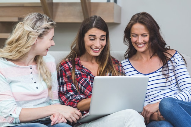 Vrienden die op bank zitten en laptop met behulp van