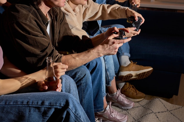 Vrienden die plezier hebben door thuis, binnenshuis, 's avonds of' s nachts gameconsole te spelen. Vriendschap, vrije tijd, rust, home party concept. Bijgesneden mensen met joysticks