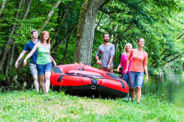 Vrienden die rubberboot dragen aan bosrivier