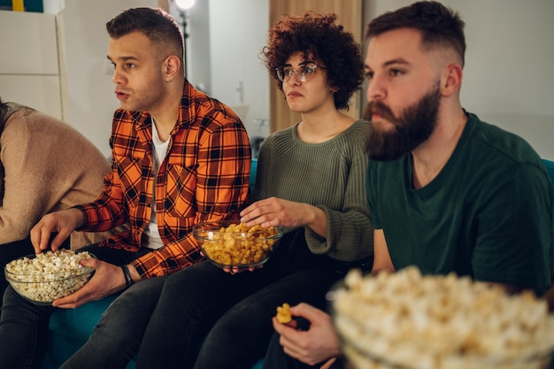 Foto vrienden die thuis film kijken en snacks eten