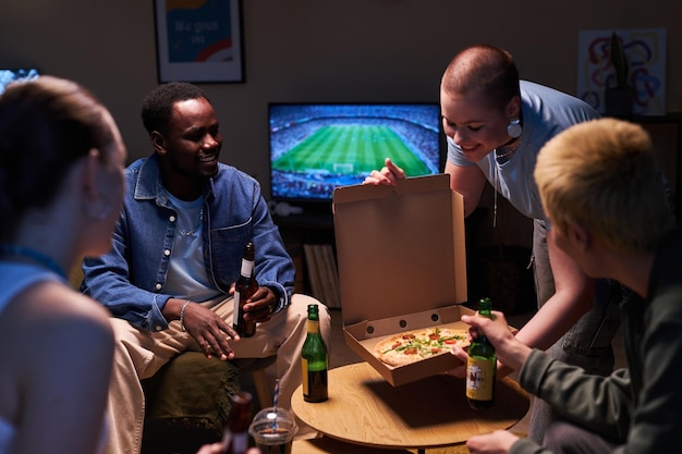 Vrienden die thuis pizza eten en voetbal kijken.