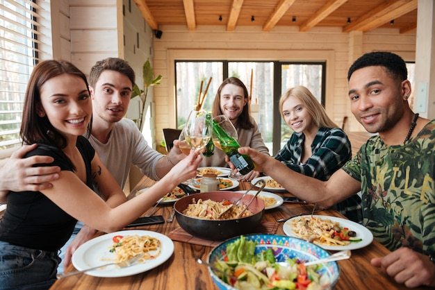 Vrienden die wijn drinken en glazen rammelen op de keuken