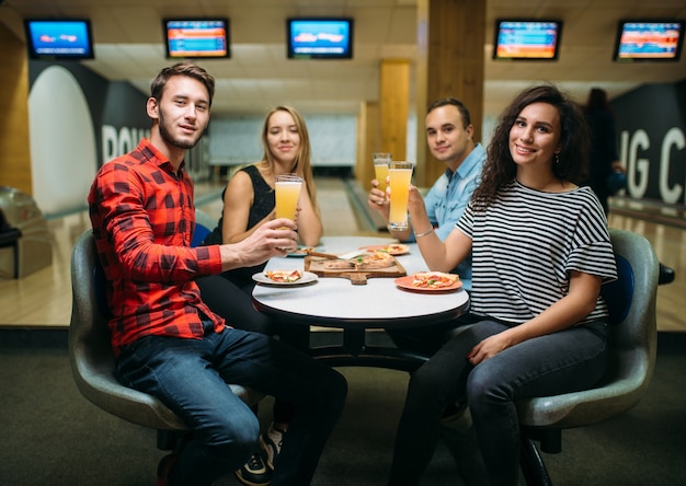 Vrienden drinkt sap en eet pizza in de bowlingclub