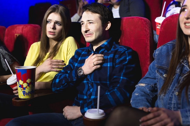 Vrienden, een man en een vrouw kijken huilend naar een film in een bioscoop.