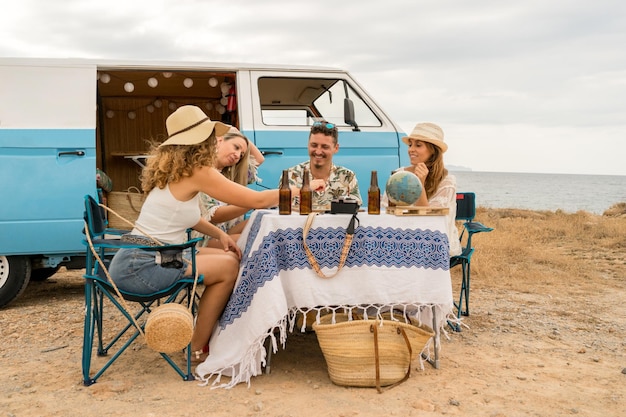 Vrienden eten naast een camper op het strand