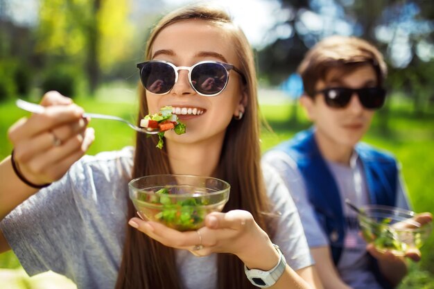 Foto vrienden genieten van een gezonde maaltijd jongen en meisje eten gezond voedsel gezonde levensstijl concept picknick