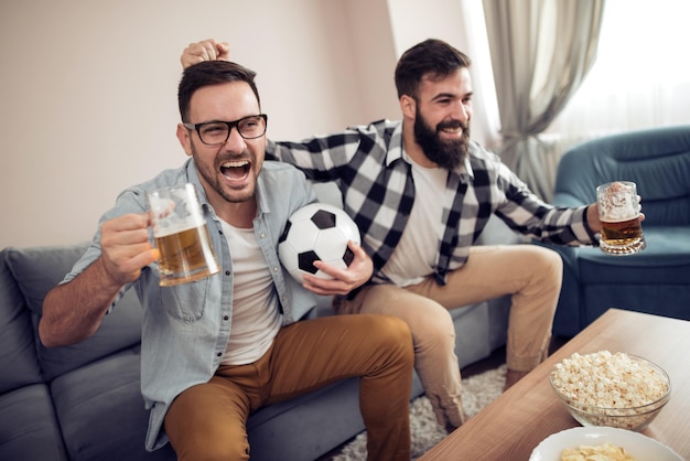 Vrienden genieten van voetbal op tv