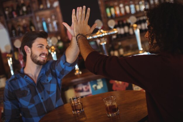 Vrienden geven high five terwijl ze drinken