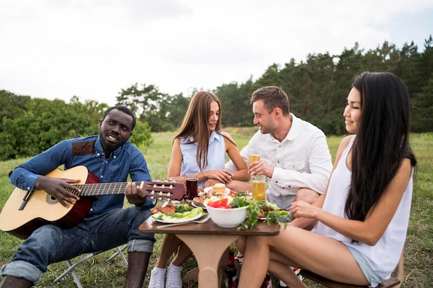 Vrienden gitaarspelen en eten bij een barbecue