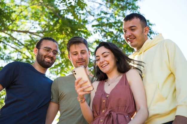 Vrienden glimlachen terwijl ze naar een mobiele telefoon kijken