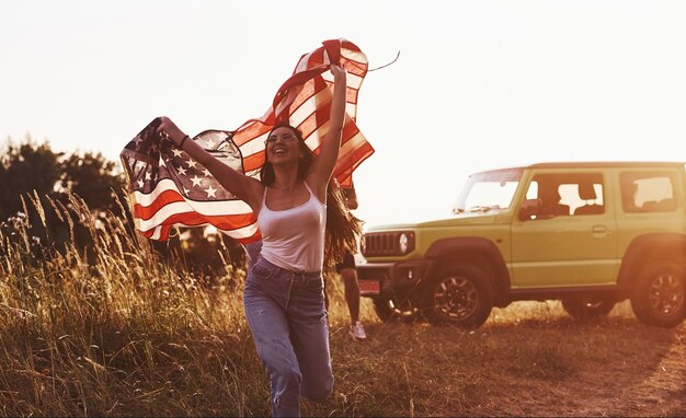 Vrienden hebben een leuk weekend buiten in de buurt van hun groene auto met Amerikaanse vlag